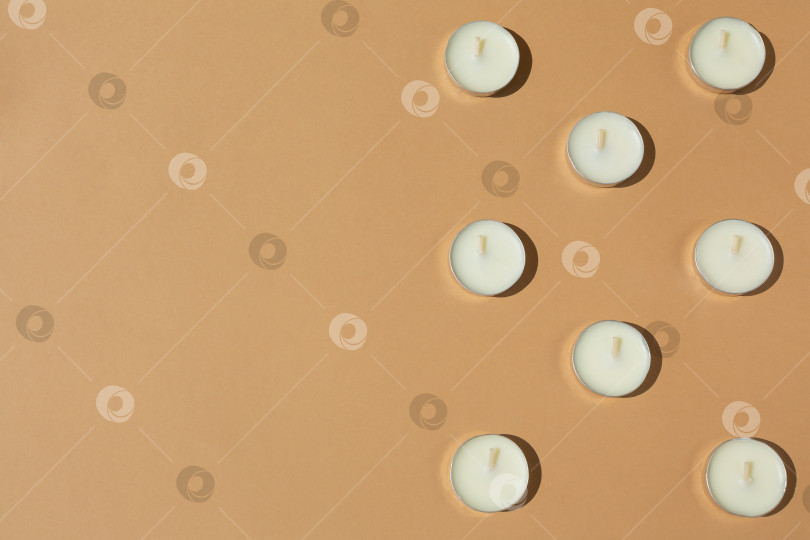 Скачать белые свечи на бежевом или коричневом фоне. Контрастное освещение. Ровная поверхность. Изображение сверху. Вид сверху. Место для вашего текста фотосток Ozero