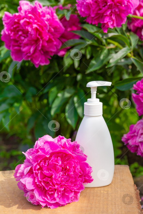 Скачать белая косметическая бутылочка для мыла или шампуня на деревянной полке на фоне пионов. Для демонстрации вашего продукта фотосток Ozero