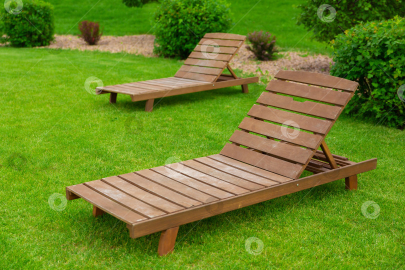 Скачать Реклама отдыха и туризма. Два пустых коричневых деревянных шезлонга на зеленой траве свежего газона фотосток Ozero