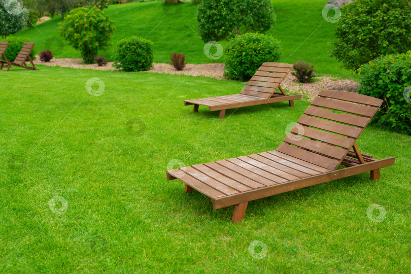 Скачать Реклама для отдыха и туризма. Два пустых коричневых деревянных шезлонга на зеленой траве свежего газона фотосток Ozero