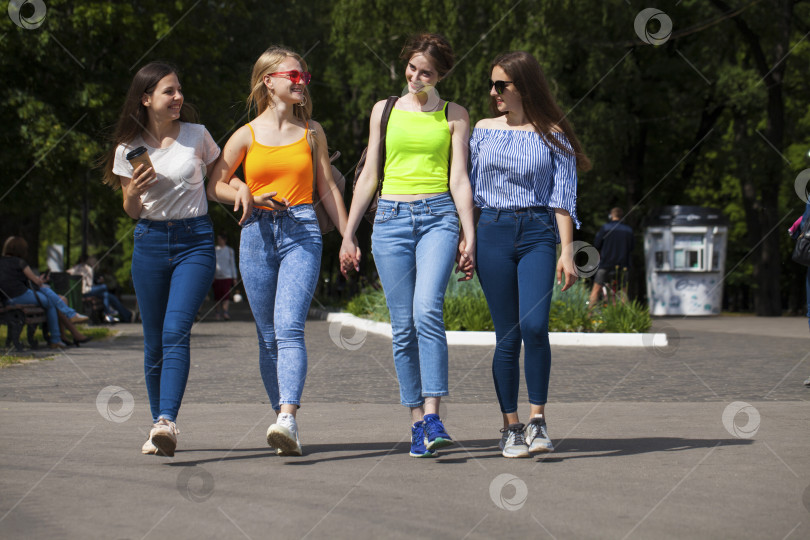 Скачать Счастливые женщины в синих джинсах прогуливаются по летнему парку фотосток Ozero