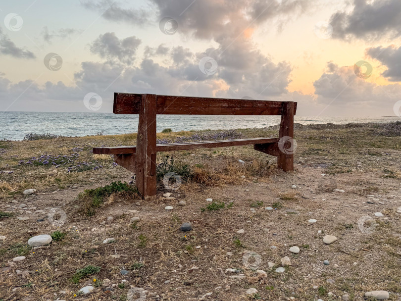 Скачать Уединенная деревянная скамейка на берегу моря на закате, предлагающая место для созерцания и оценки красоты природы на фоне яркого неба. фотосток Ozero