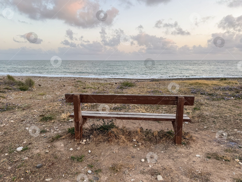 Скачать Безмятежный вид на море С пустой деревянной скамьей, откуда открывается вид на Спокойный океан и мягкие облака в сумерках фотосток Ozero