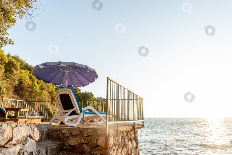 Скачать Оборудованный галечный пляж Адриатического моря, пустые шезлонги на закате, Утеха, Черногория фотосток Ozero