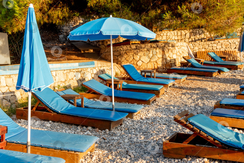 Скачать Оборудованный галечный пляж Адриатического моря, пустые шезлонги на закате, Утеха, Черногория фотосток Ozero