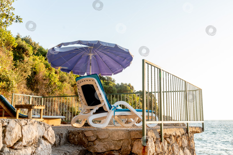 Скачать Оборудованный галечный пляж Адриатического моря, пустые шезлонги на закате, Утеха, Черногория фотосток Ozero