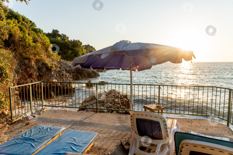 Скачать Оборудованный галечный пляж Адриатического моря, пустые шезлонги на закате, Утеха, Черногория фотосток Ozero