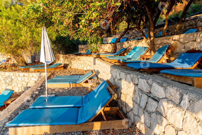 Скачать Оборудованный галечный пляж Адриатического моря, пустые шезлонги на закате, Утеха, Черногория фотосток Ozero