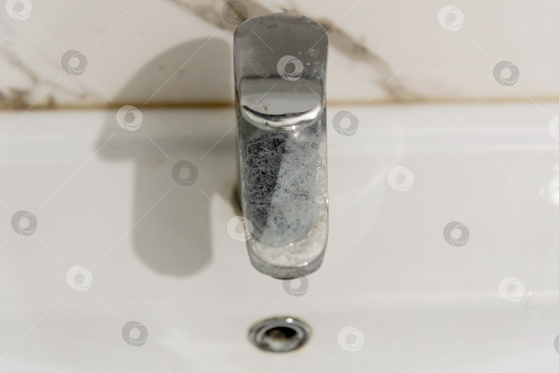 Скачать Грязный хромированный кран в ванной комнате покрылся налетом извести из-за жесткой воды фотосток Ozero