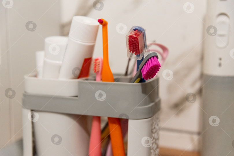 Скачать Зубные щетки и зубные пасты для полости рта в пластиковом контейнере на полке в ванной комнате фотосток Ozero