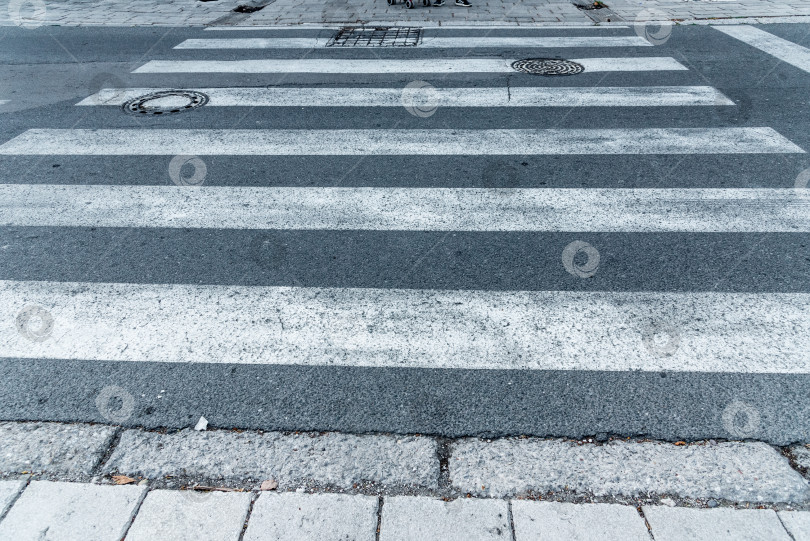 Скачать Пешеходная зебра, пересекающая белые полосы на асфальтированной серо-черной дороге с интенсивным движением фотосток Ozero