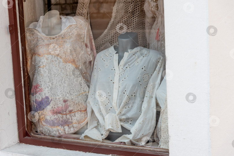Скачать Манекен с женской рубашкой и платьем стоит за стеклянной витриной магазина одежды фотосток Ozero