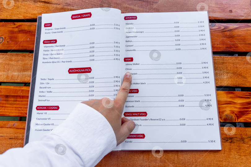 Скачать Цетинье, Черногория, 3 августа 2025 года, Посетитель кафе перебирает меню и выбирает фотосток Ozero