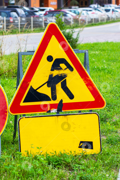 Скачать Предупреждающий знак, указывающий на строительные работы, размещенный на Зеленой траве фотосток Ozero