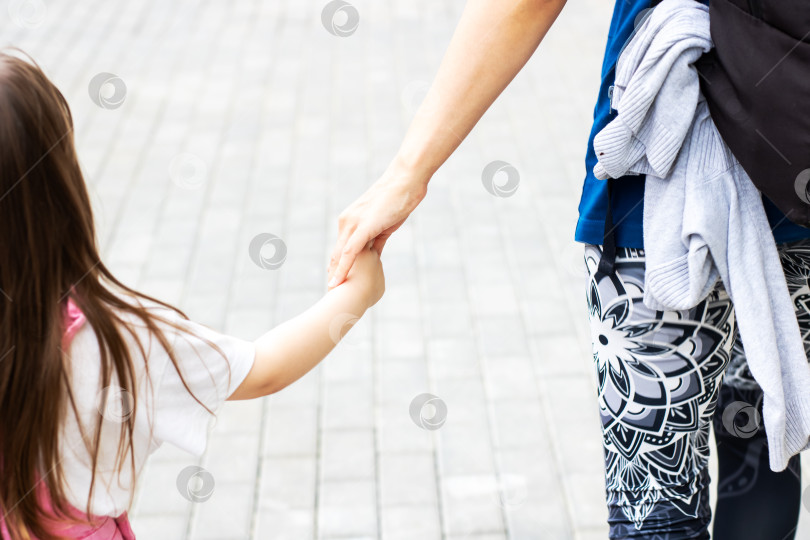Скачать Родитель и ребенок прогуливаются, взявшись за руки, по парку фотосток Ozero