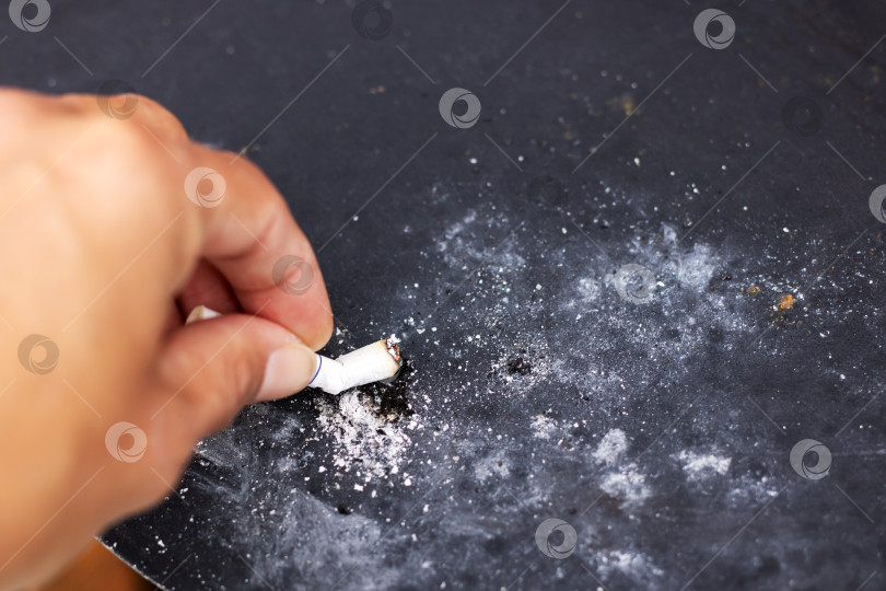 Скачать Крупный план руки, сворачивающей сигарету на черной поверхности фотосток Ozero