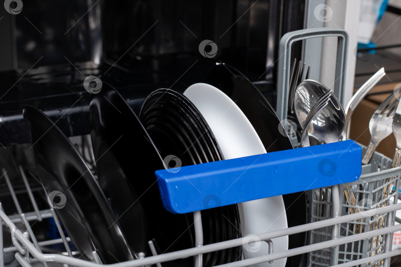 Скачать Посудомоечная машина загружена чистыми тарелками и сверкающими столовыми приборами фотосток Ozero