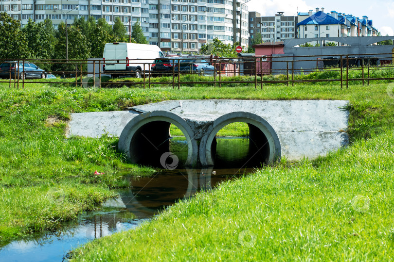 Скачать Бетонная водопропускная труба в городском ландшафте с пышной зеленой травой фотосток Ozero