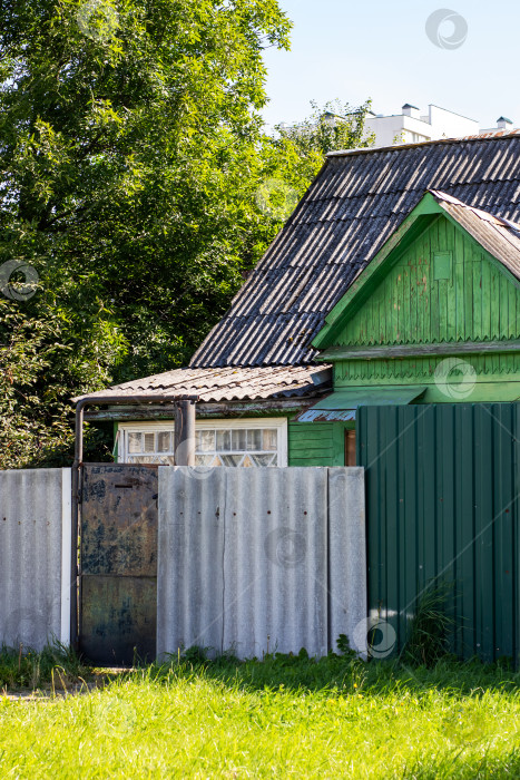Скачать Очаровательный Зеленый деревянный дом, окруженный оградой при ярком дневном свете фотосток Ozero