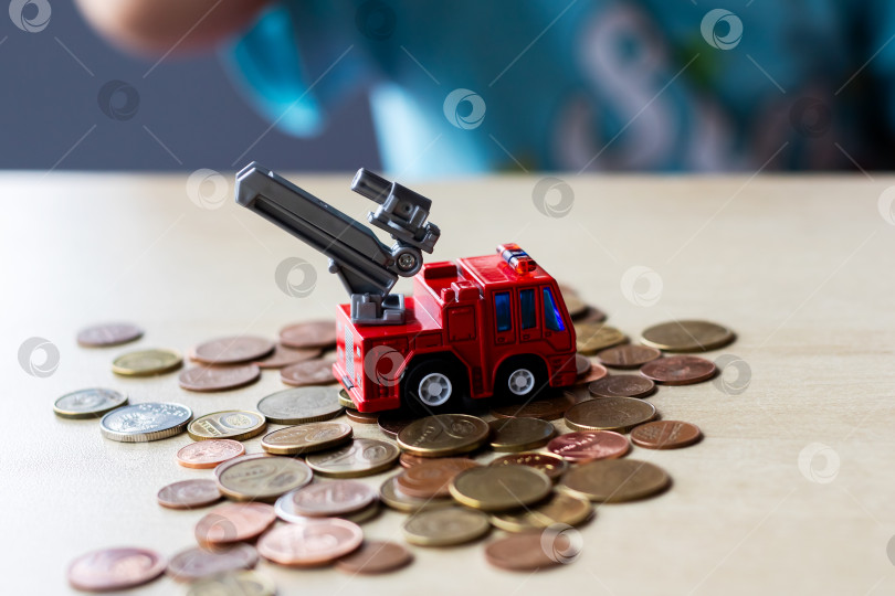 Скачать Игрушечная пожарная машина, которая окружена множеством монет фотосток Ozero