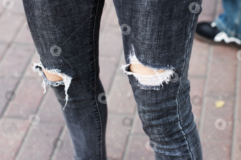 Скачать Модные потертые черные джинсы со стильным дизайном на порванных коленях фотосток Ozero