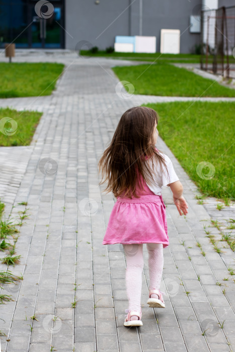 Скачать Веселый ребенок, идущий по мощеной дорожке в оживленном парке фотосток Ozero
