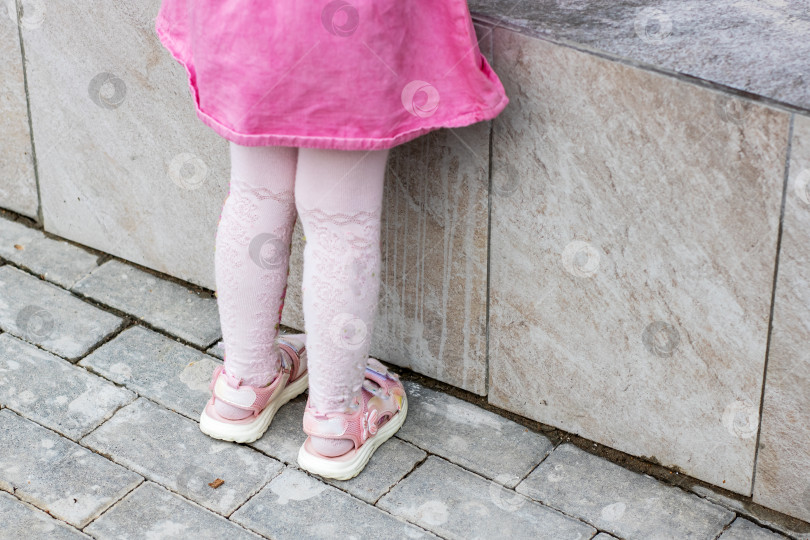 Скачать Радостная игривая поза ребенка в очаровательном розовом платье и туфельках фотосток Ozero