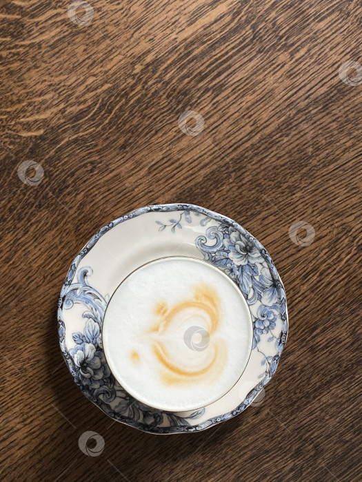 Скачать Капучино в стиле латте-арт на винтажном цветочном блюдце на деревянном столе в деревенском стиле, подходит в качестве фона фотосток Ozero