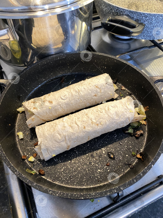 Скачать Приготовление буррито на сковороде на кухонной плите, демонстрация процесса приготовления и мексиканской кухни фотосток Ozero