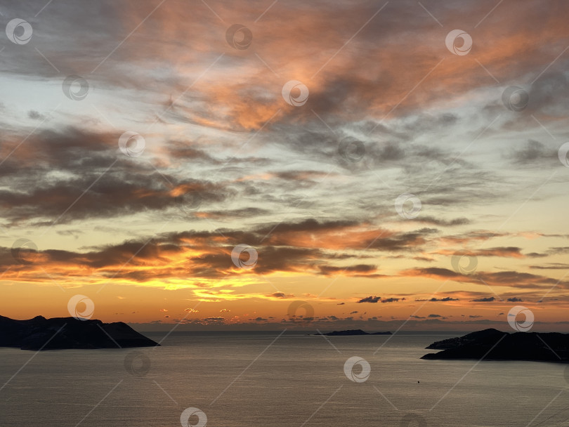 Скачать Впечатляющий закат над океаном с силуэтами островов и яркими облаками на небе - идеальный фон фотосток Ozero