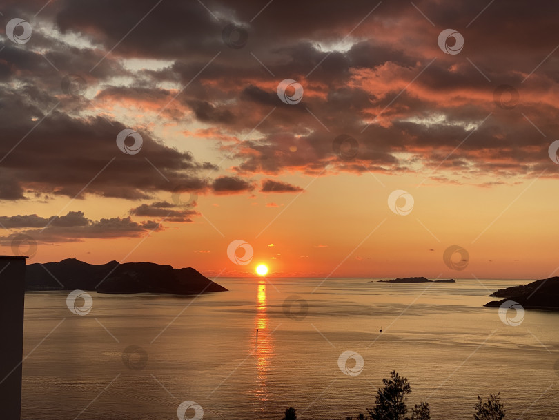Скачать Вид на закат над океанским горизонтом с эффектными облаками и силуэтами береговой линии - идеальный фон фотосток Ozero