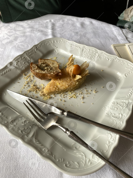 Скачать Пустая десертная тарелка с остатками выпечки и крошками на декоративной белой скатерти фотосток Ozero