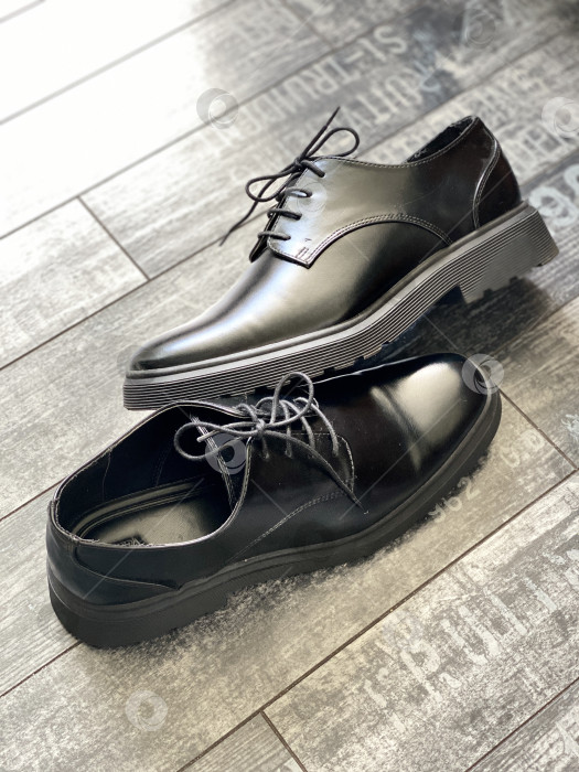 Скачать Черные кожаные модельные туфли на деревянном полу с текстурированным фоном фотосток Ozero