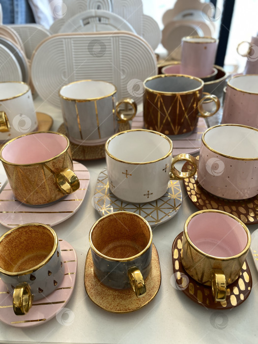 Скачать Декоративные кофейные кружки с золотыми вставками на столешнице при мягком освещении, подходящие для фона фотосток Ozero