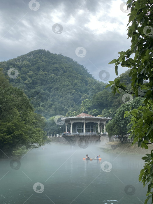 Скачать Туманное озеро со зданием и горой в туманном пейзаже, идеально подходящее для безмятежного фона фотосток Ozero