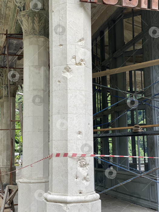 Скачать Архитектурная реставрация исторической каменной колонны в стадии ремонта с использованием строительных лесов и защитной ленты фотосток Ozero