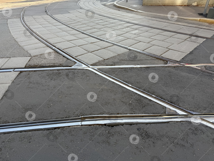 Скачать Трамвайные пути пересекаются на городской улице, создавая геометрический узор на бетонном и асфальтовом фоне фотосток Ozero