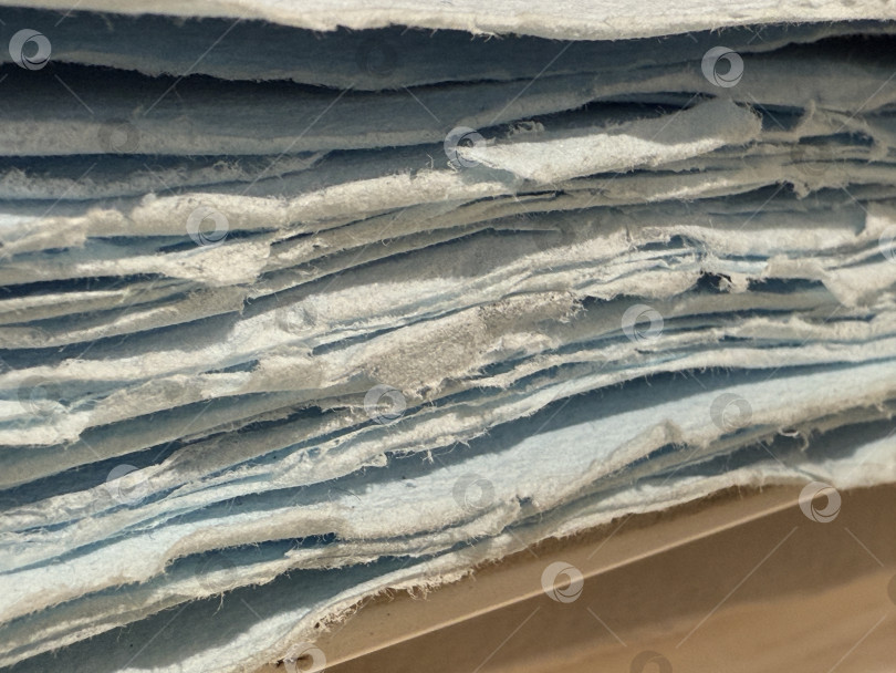 Скачать Крупный план сложенных в стопку листов синей бумаги, создающих текстурированный абстрактный узор, подходящий в качестве фона фотосток Ozero