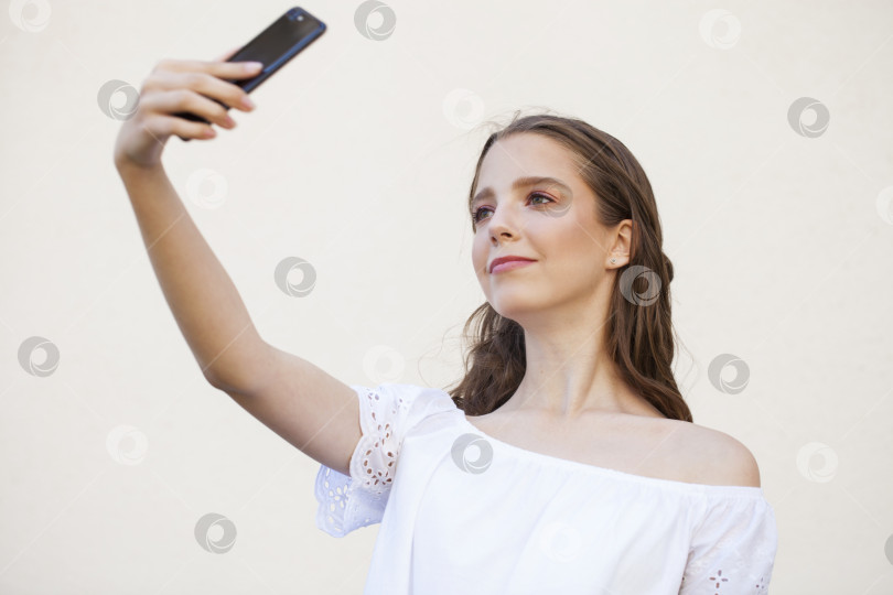 Скачать Симпатичная молодая брюнетка делает селфи на смартфоне фотосток Ozero