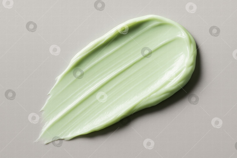 Скачать Эстетичное нанесение гладкого светло-зеленого крема или лосьона на нейтральную поверхность, передающее суть текстуры и цвета средств по уходу за кожей. фотосток Ozero