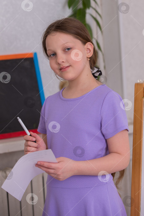Скачать Молодая девушка держит ручку и бумагу в классе, готовясь писать во время занятия искусством во второй половине дня фотосток Ozero