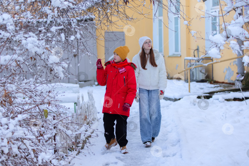 Скачать Мальчик и девочка в зимней одежде прогуливаются перед домом. фотосток Ozero