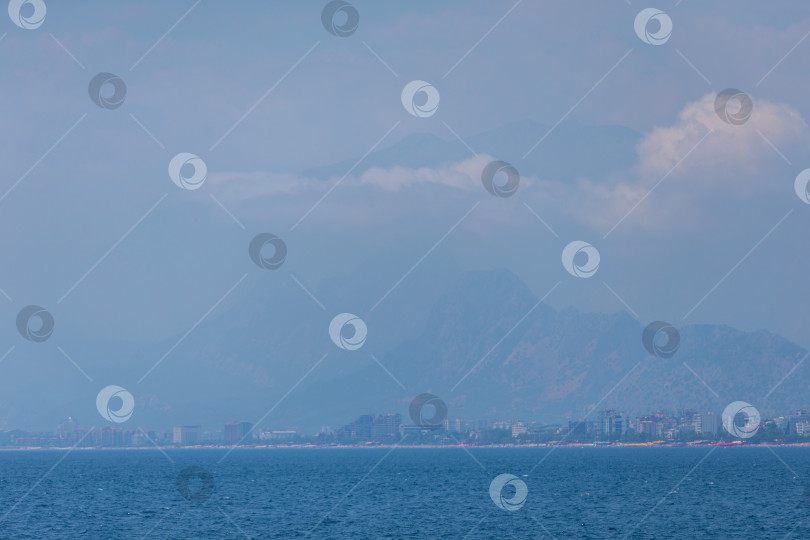 Скачать Пейзаж с синим морем и городом, размытым вдалеке рядом с горой. фотосток Ozero