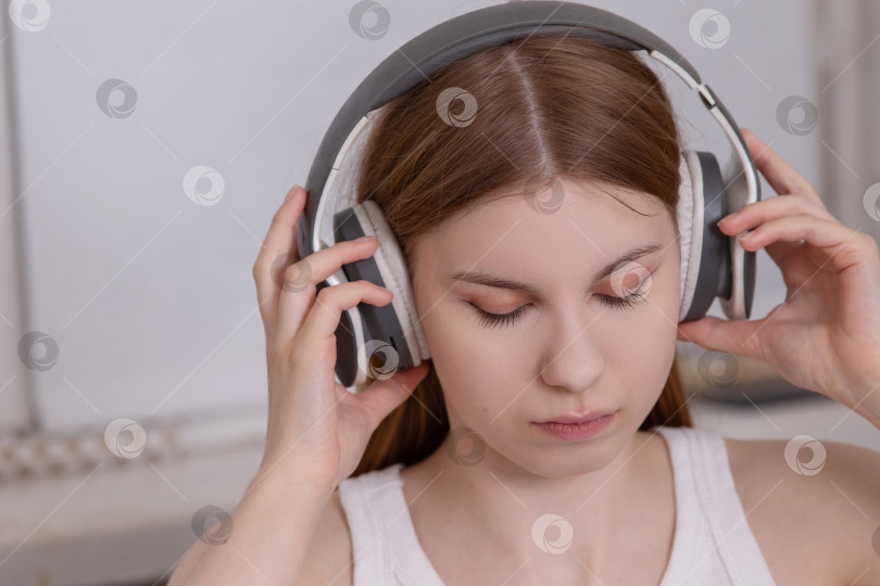 Скачать Молодая женщина в наушниках слушает музыку в уютном помещении во второй половине дня фотосток Ozero