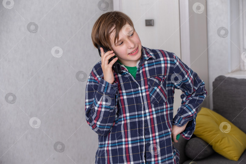 Скачать Мальчик разговаривает по телефону в уютной домашней обстановке во время спокойного послеобеденного отдыха фотосток Ozero