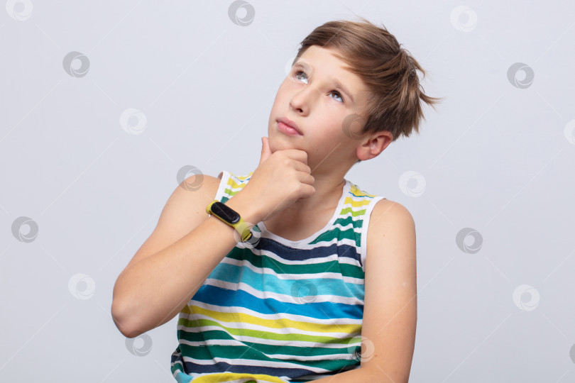 Скачать Молодой парень с задумчивым выражением лица обдумывает свои мысли на простом фоне фотосток Ozero