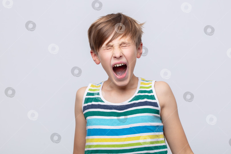 Скачать Молодой парень, выражающий волнение во время крика, в полосатой майке-безрукавке на простом фоне фотосток Ozero