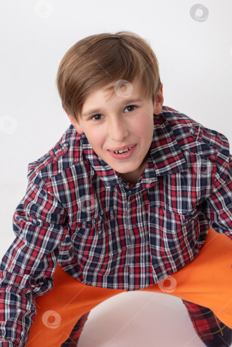 Скачать Мальчик-подросток в клетчатой рубашке смотрит в камеру и улыбается. фотосток Ozero