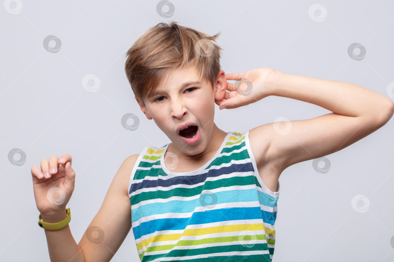 Скачать Ребенок зевает и потягивается в яркой полосатой майке в помещении при ярком освещении фотосток Ozero