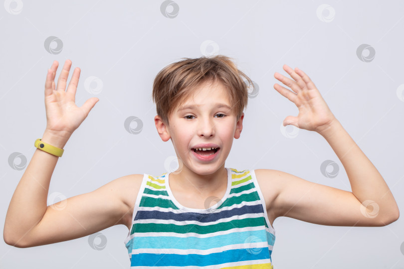 Скачать Возбужденный мальчик, выражающий радость поднятыми руками в веселой обстановке в дневное время фотосток Ozero